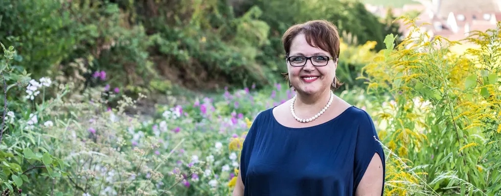 Eine Frau steht auf einem Feld und blickt in die Kamera.