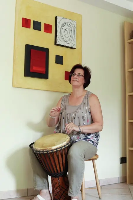 Gabi trommelt in ihrem Wohnzimmer auf der afrikanischen Trommel Djembé.