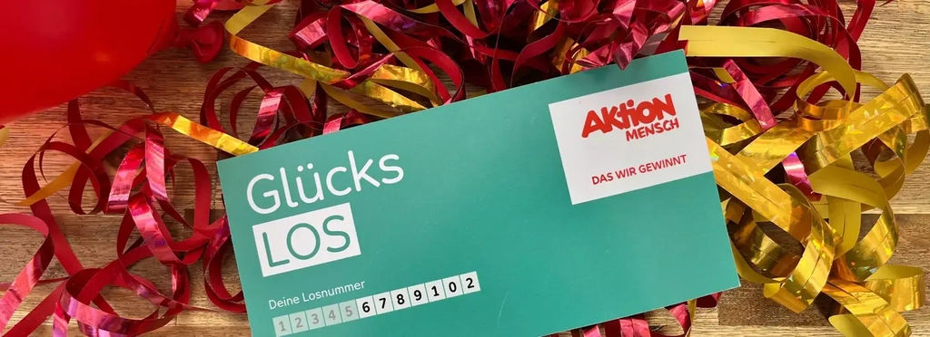 Ein Glücks-Los liegt auf einem Haufen rot-goldener Luftschlangen.