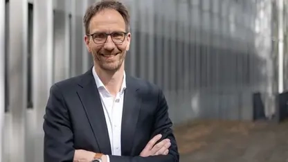 Ein Portrait von Prof. Dr. Thomas Abel. Er steht lächelnd vor einem Gebäude und hat die Arme locker vor dem Oberkörper verschränkt