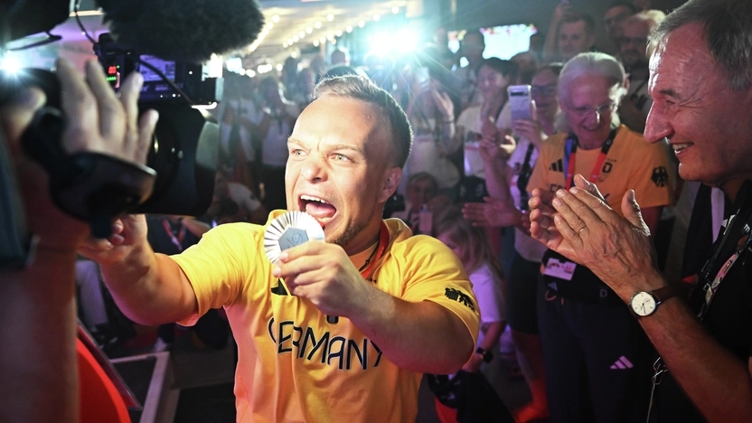 Der Para Kugelstoßer Niko Kappel präsentiert seine Medaille in Richtung einer Fernsehkamera im Deutschen Haus Paralympics in Paris 2024.