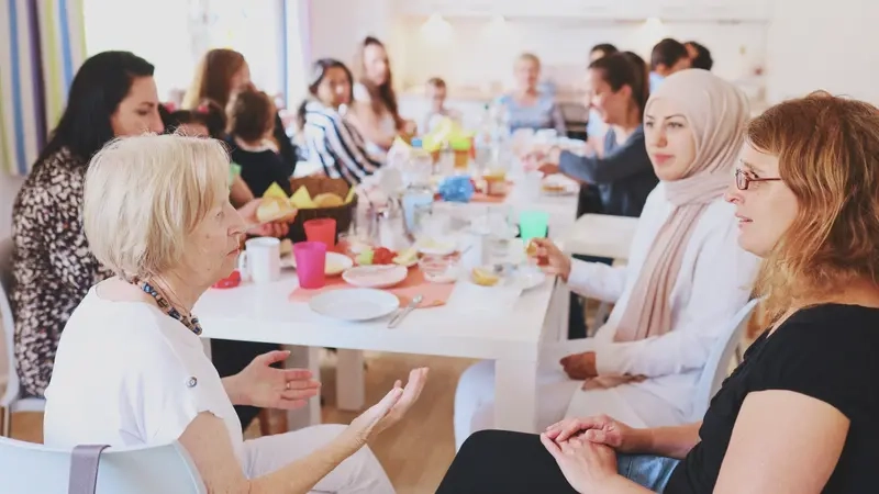 Frauen jeden Alters sitzen an einem Tisch und sind im Gespräch. Sie frühstücken.