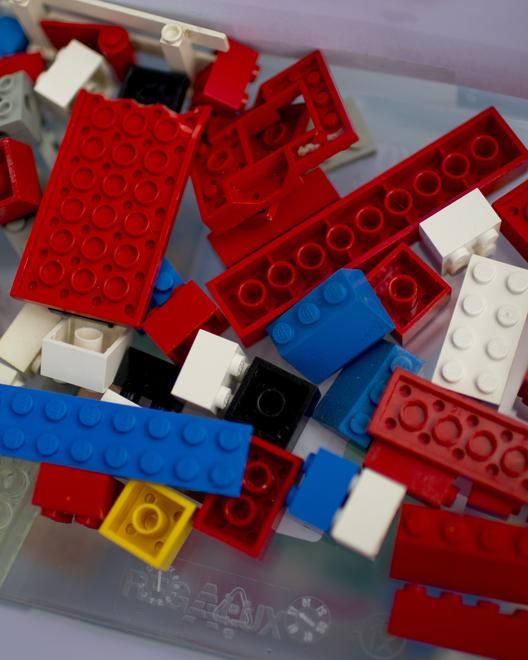 In einer transparenten Box lieben Legosteine unterschiedlicher Form und Farbe.