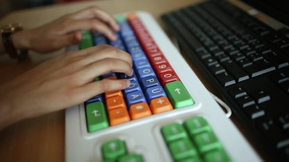 Zwei Hände auf einer bunten Tastatur.