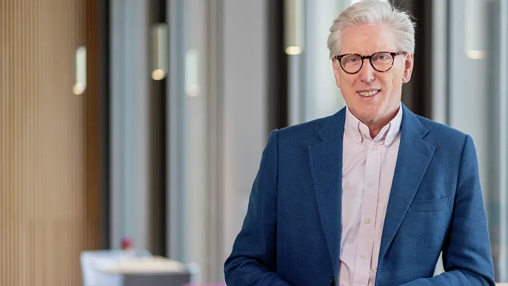 Grauhaariger Mann Mitte sechzig mit Brille in blauer Anzugsjacke