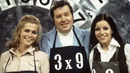 Wim Thoelke und zwei junge Frauen tragen eine schwarze Schürze mit der Aufschrift 3x9.