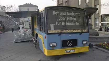 Ein blau-gelber Bus mit dem Schriftzug "Rat und Auskunft über Hilfen für Behinderte" auf de Windschutzscheibe.