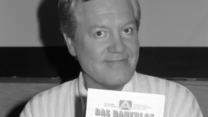 Wim Thoelke hält ein Dauerlos der Aktion Sorgenkind in der Hand.