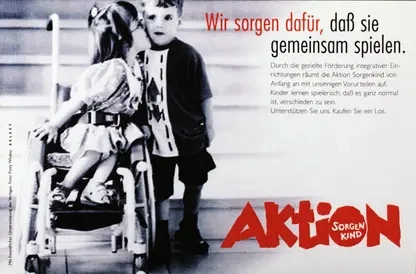 Ein Mädchen im Rollstuhl küsst einen Jungen neben ihr auf die Wange. Rechts steht der Schriftzug "Wir sorgen dafür, dass sie gemeinsam spielen".