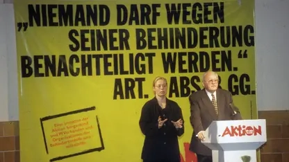 Roman Herzog steht auf einem Podium. Neben ihm steht eine Gebärdensprachdolmetscherin. Im Hintergrund ist ein Plakat mit der Aufschrift "Niemand darf wegen seiner Behinderung benachteiligt werden." zu sehen.
