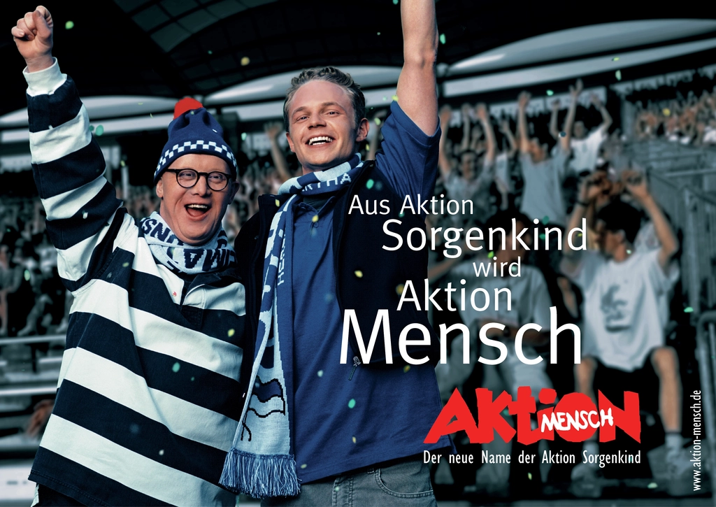 Ein Mann mit Down-Syndrom und ein junger Mann im blauen Hemd jubelnd. Es ist der Schriftzug "Aus Aktion Sorgenkind wird Aktion Mensch" zu lesen.