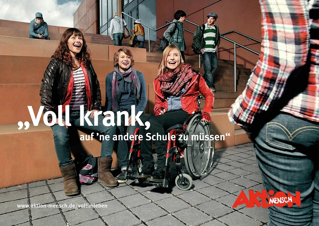 Drei Mädchen auf einem Schulhof lachen einen Jungen an. Ein Mädchen sitzt im Rollstuhl.