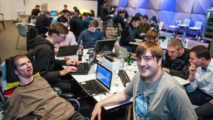 Ein Raum mit Menschen, die an Tischen mit Notebooks sitzen.