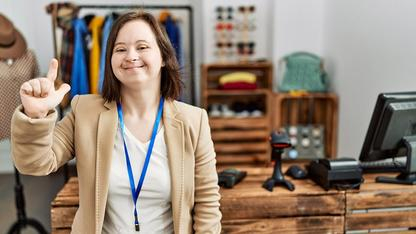 Eine Frau mit Down Syndrom steht in einem Büro.