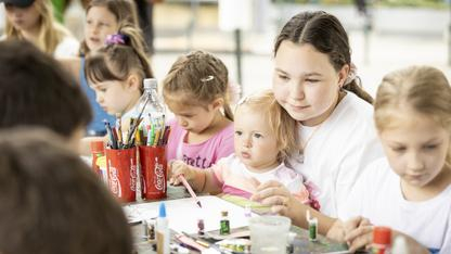 Kinder verschiedenen Alters sitzen gemeinsam an einem Tisch und malen und basteln.