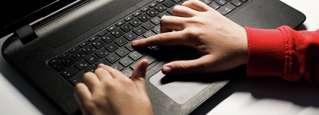 Eine Laptop-Tastatur, darauf zwei Hände.