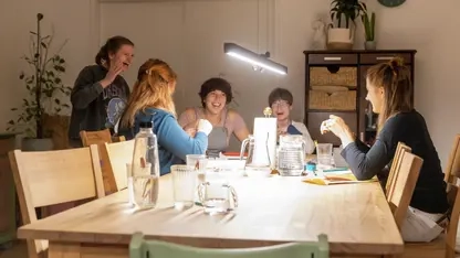 Fünf junge Frauen lachen an einem großen Tisch.