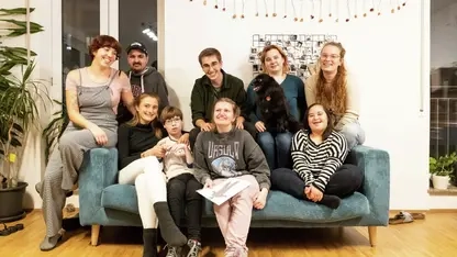 Eine Gruppe von Menschen mit uns ohne Behinderung sitzt gemeinsam auf einem Sofa