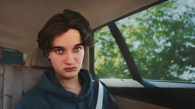 Ein Junge sitzt auf der Rückbank im Auto. Er starrt ins Leere.