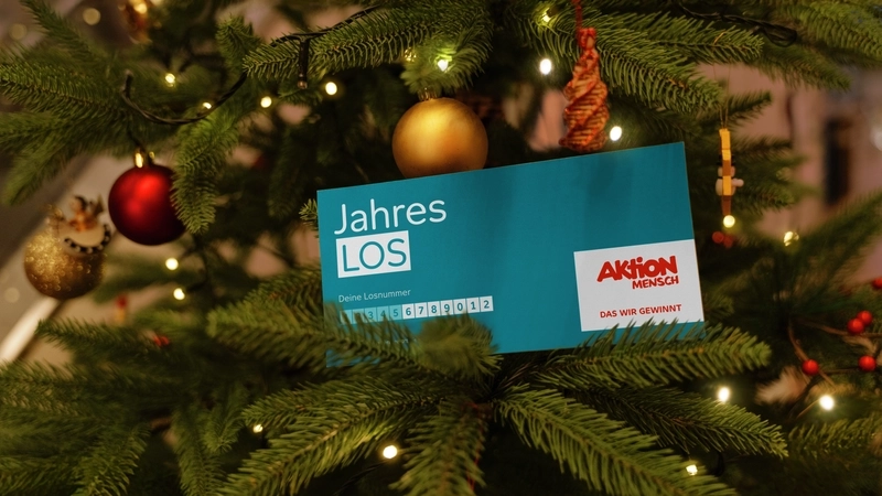 In einem Weihnachtsbaum steht ein Jahreslos der Aktion Mensch.