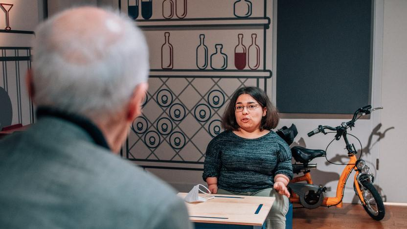 Eine junge kleinwüchsige Frau spricht in einem Studio mit einem Mann