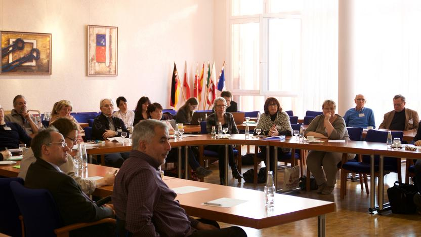 Viele Menschen sitzen an einem Konferenztisch