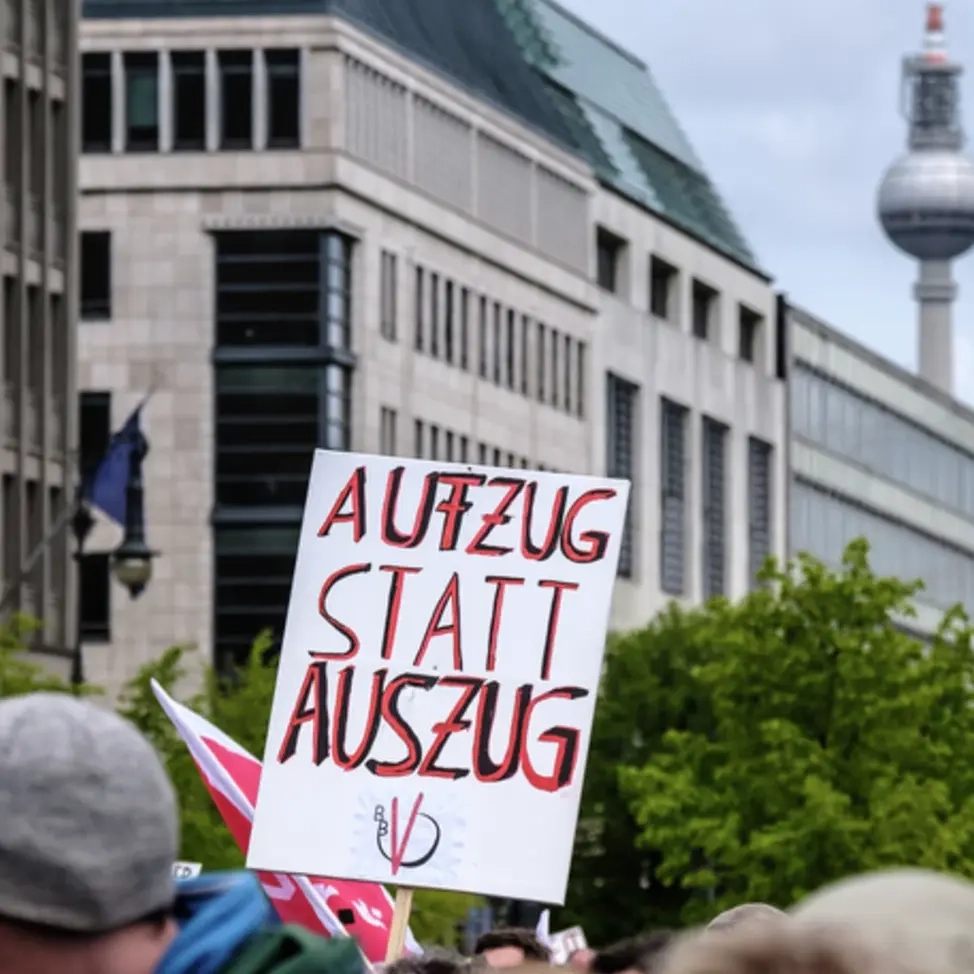 Demoschild mit der Aufschrift "Aufzug statt Auszug" ragt über die Köpfe von Demonstrierenden