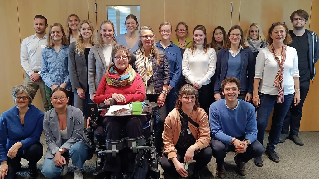 Ein Gruppe von Menschen mit und ohne Behinderung steht zusammen und schaut in die Kamera.