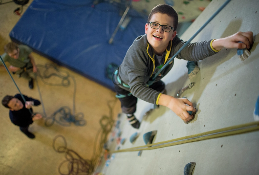 Ein Junge klettert an einer Kletterwand. 