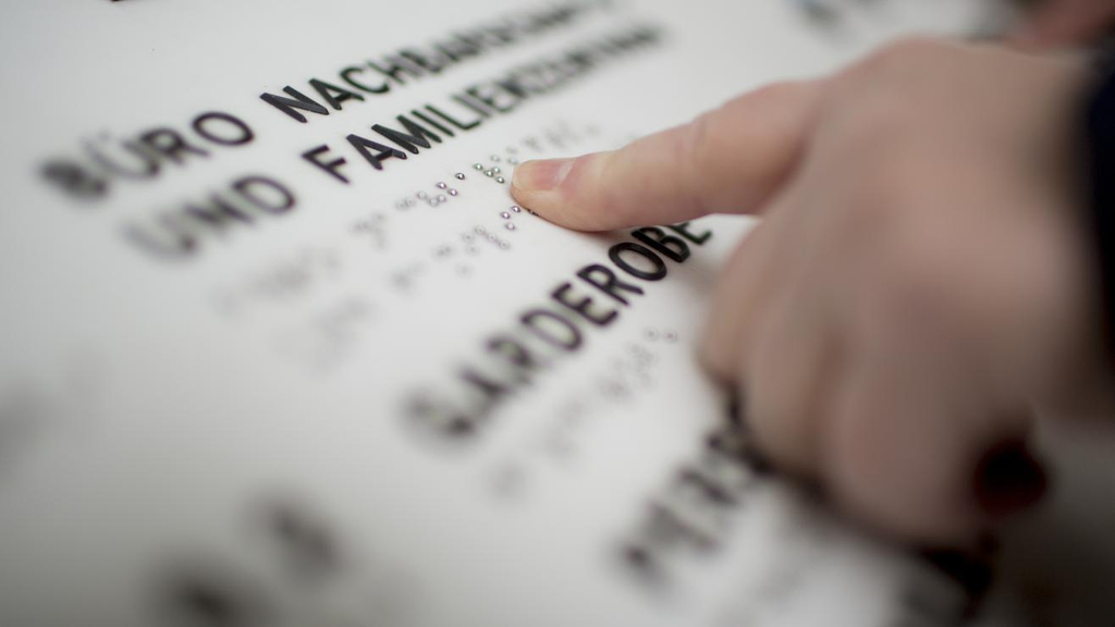 Eine Kinderhand liest einen Text in Brailleschrift. 