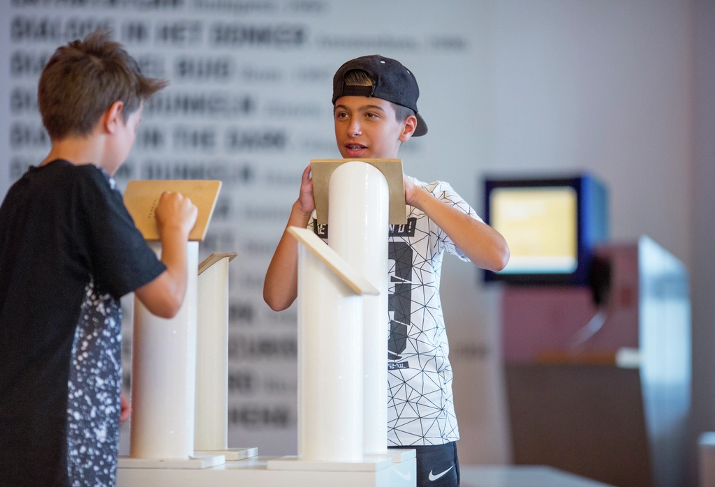 Zwei Jungen stehen in einem Museum an einem Ausstellungsstück und sehen es sich an. 