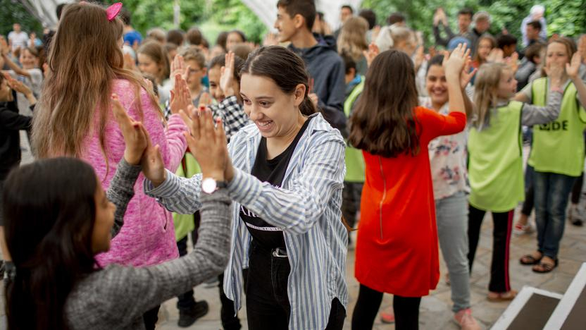 Mehrere Kinder in Zweiergruppen. Jede Zweiergruppe klatscht sich ab.