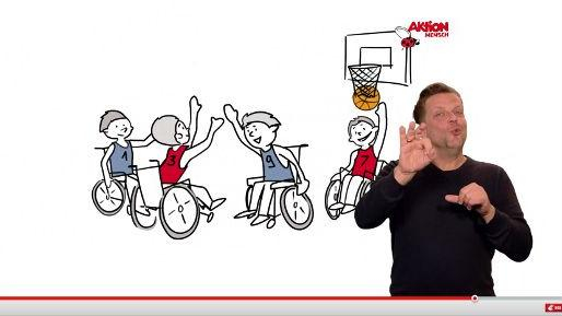 Bild eines Video-Players: Am rechten Rand des Videos, das gezeichnete Rollstuhlbasketballer zeigt, übersetzt ein Gebärdensprachdolmetscher