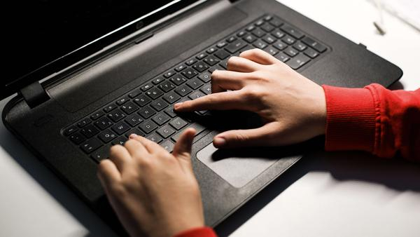 Eine Laptop-Tastatur, darauf zwei Hände.