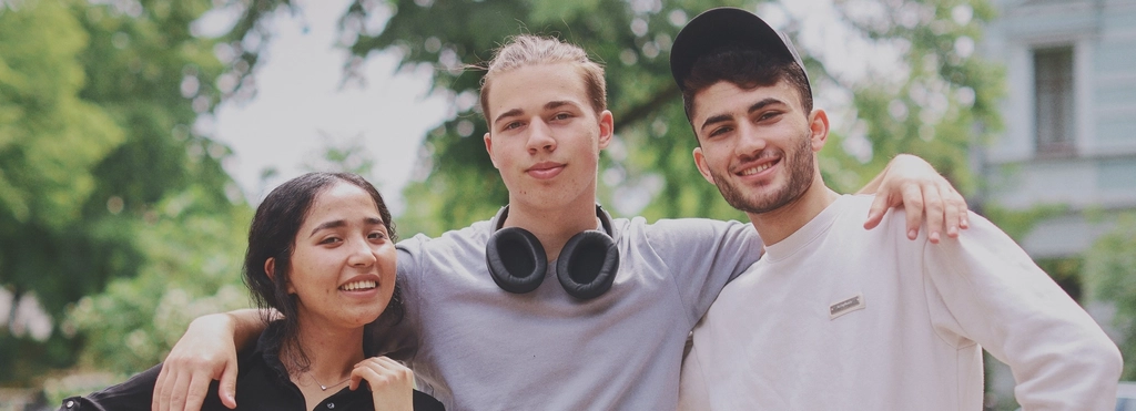 Zwei junge Männer und eine junge Frau stehen nebeneinander