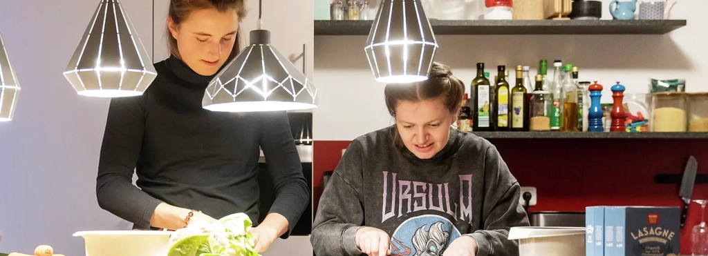 Zwei Frauen stehen in einer Küche und schneiden Gemüse.