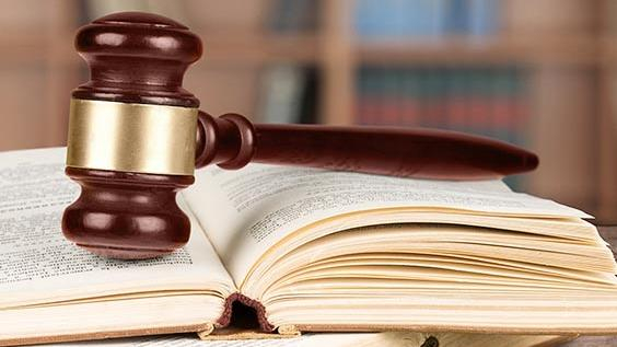 Ein Richterhammer liegt auf einem aufgeschlagenen Buch.