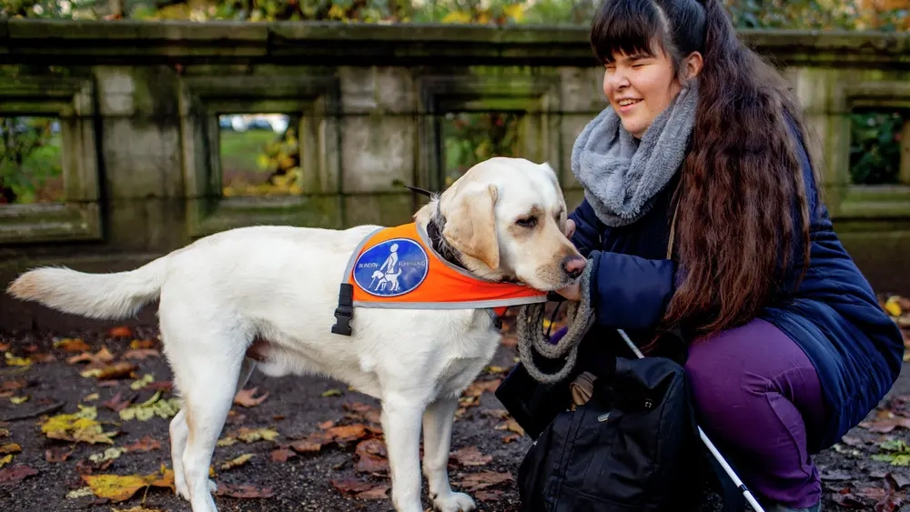 Carina kniet neben ihrem Blindenhund Pitou.
