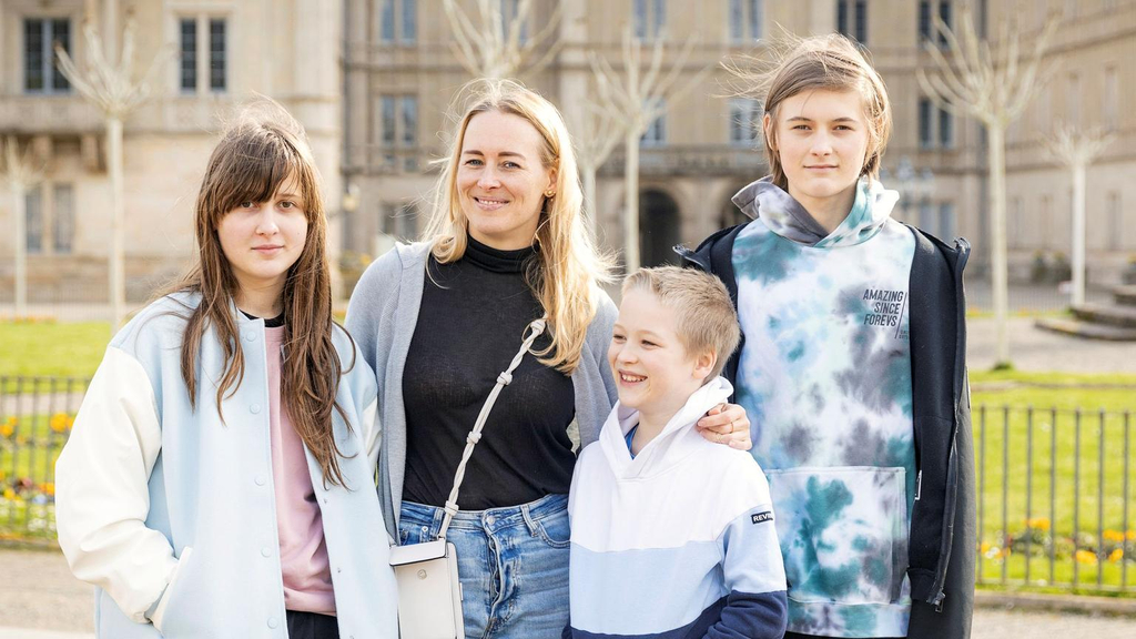 Familienbild einer Mutter mit ihren drei Kindern vor einer Schlossanlage.