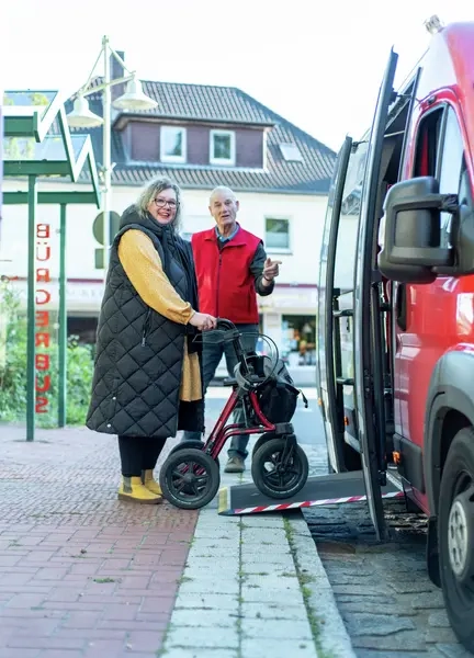 Eine Frau mit Rollator geht über eine Rampe in einen Bus