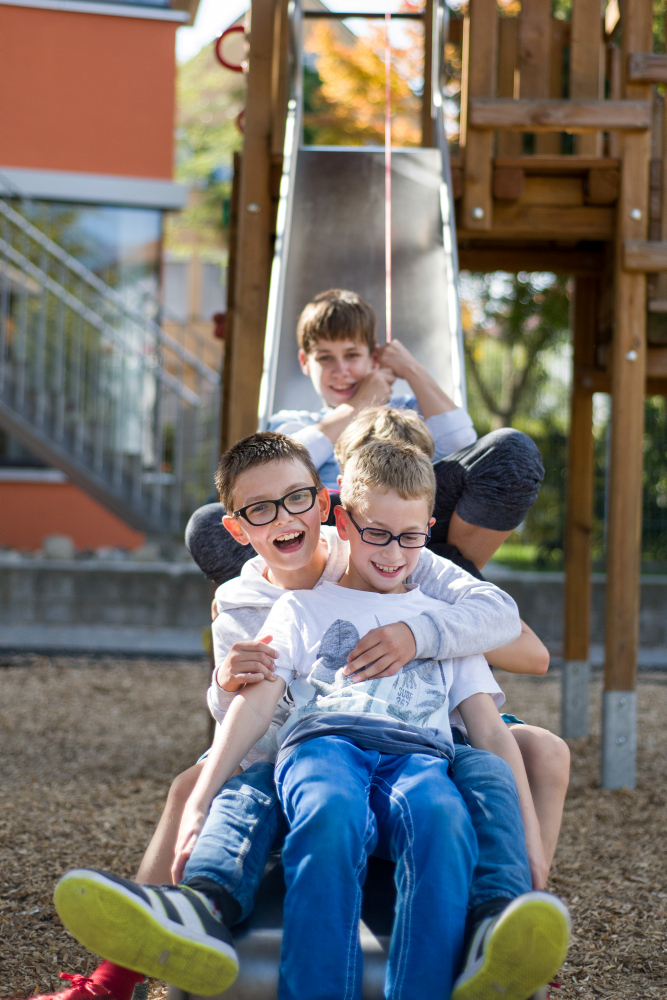 Vier Jungen rutschen gemeinsam eine Rutsche herunter