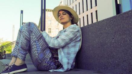 Clara Belz sitzt mit Sonnenhut auf einer großen Steintreppe.