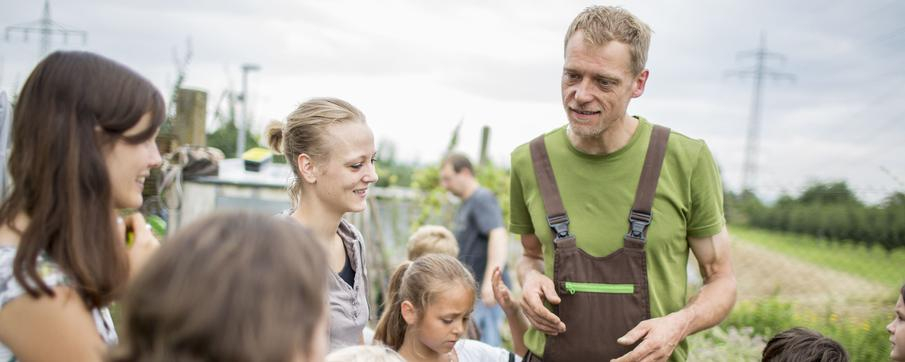 Ein Mann und Kinder arbeiten auf einem Acker.