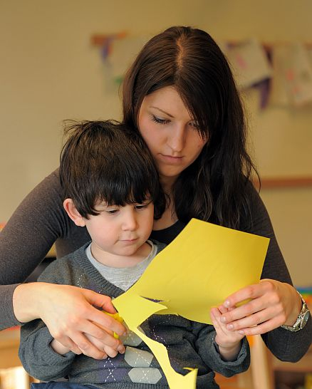 Eine Frau schneidet mit einem Kleinkind etwas aus