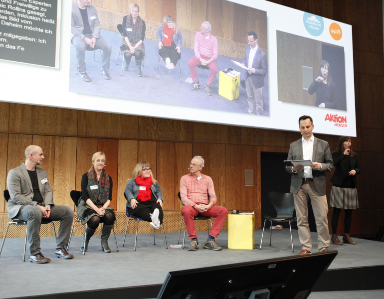 Redner sitzen bei einer Expertenrunde auf einer Bühne.