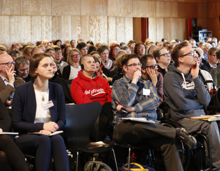 Ein Saal voller Menschen bei einem Vortrag im Plenum.