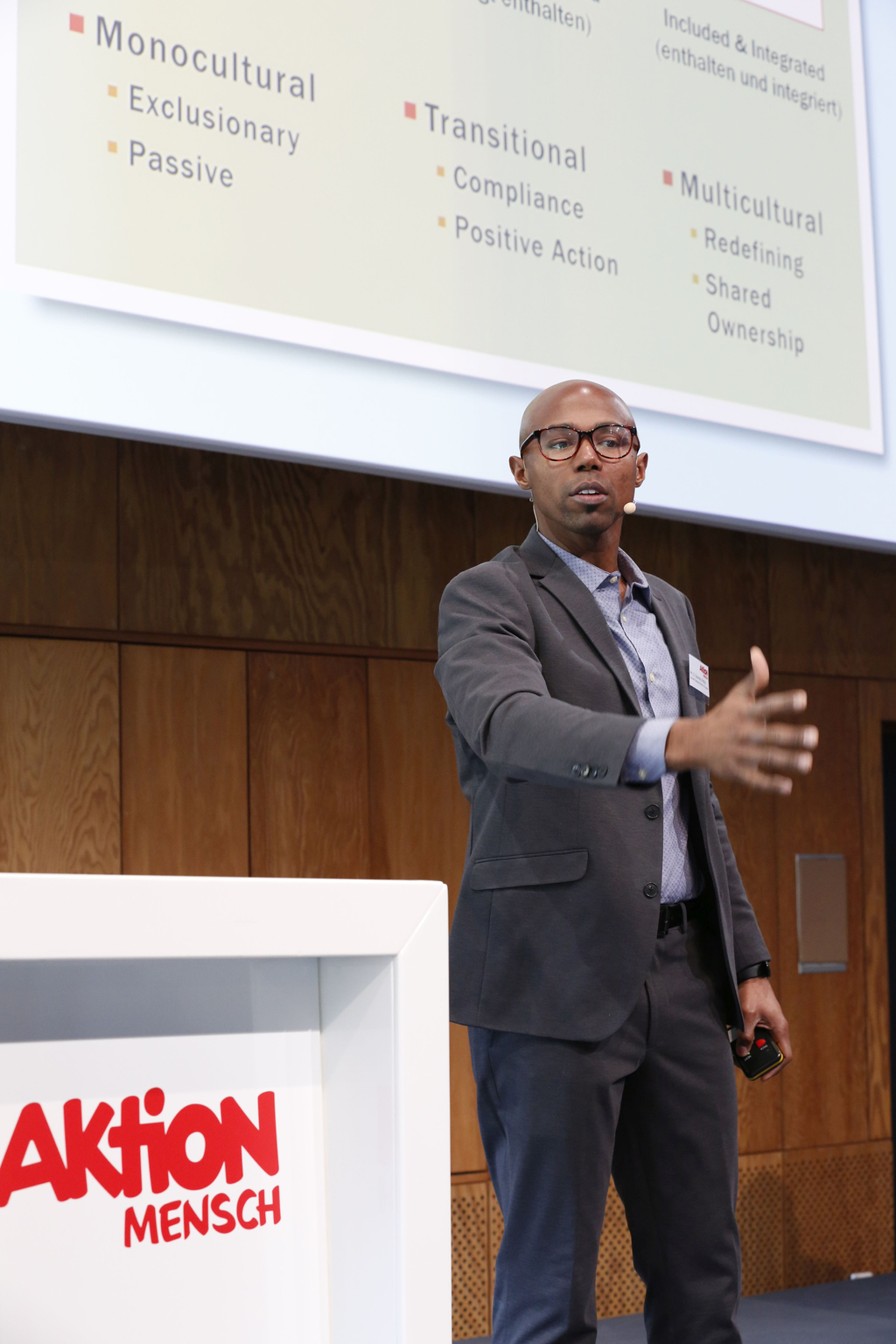 Domonic Rollins, PhD, in Großaufnahme auf der Bühne. Er reicht dem Publikum die Hand