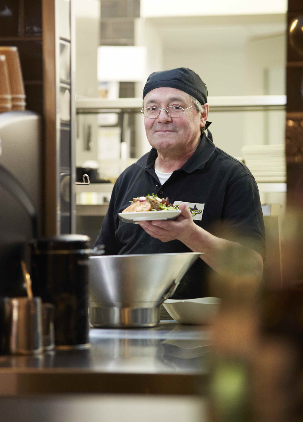Mann hält einen Teller mit einem Burger in der Hand