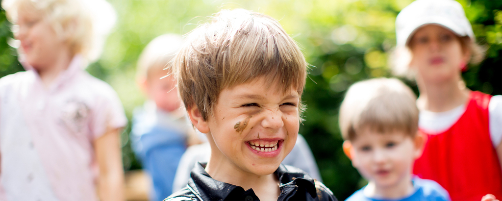 Ein Junge mit schmutzigem Gesicht lacht.