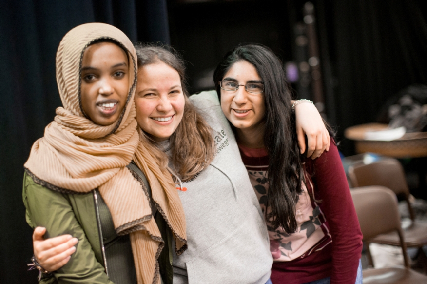 Drei Schülerinnen Arm in Arm bei einer Theaterprobe.